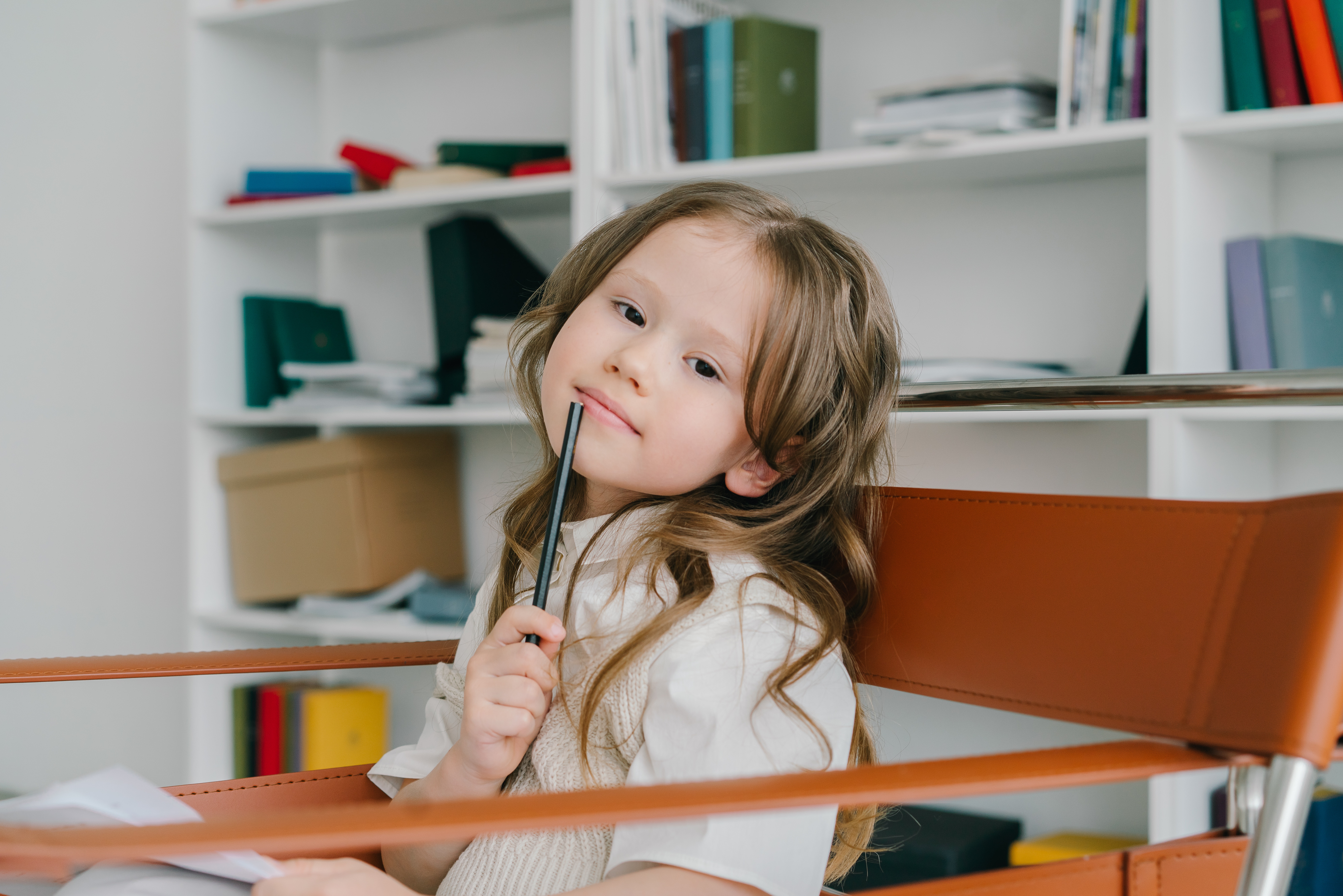 A female child holding a pen while thinking